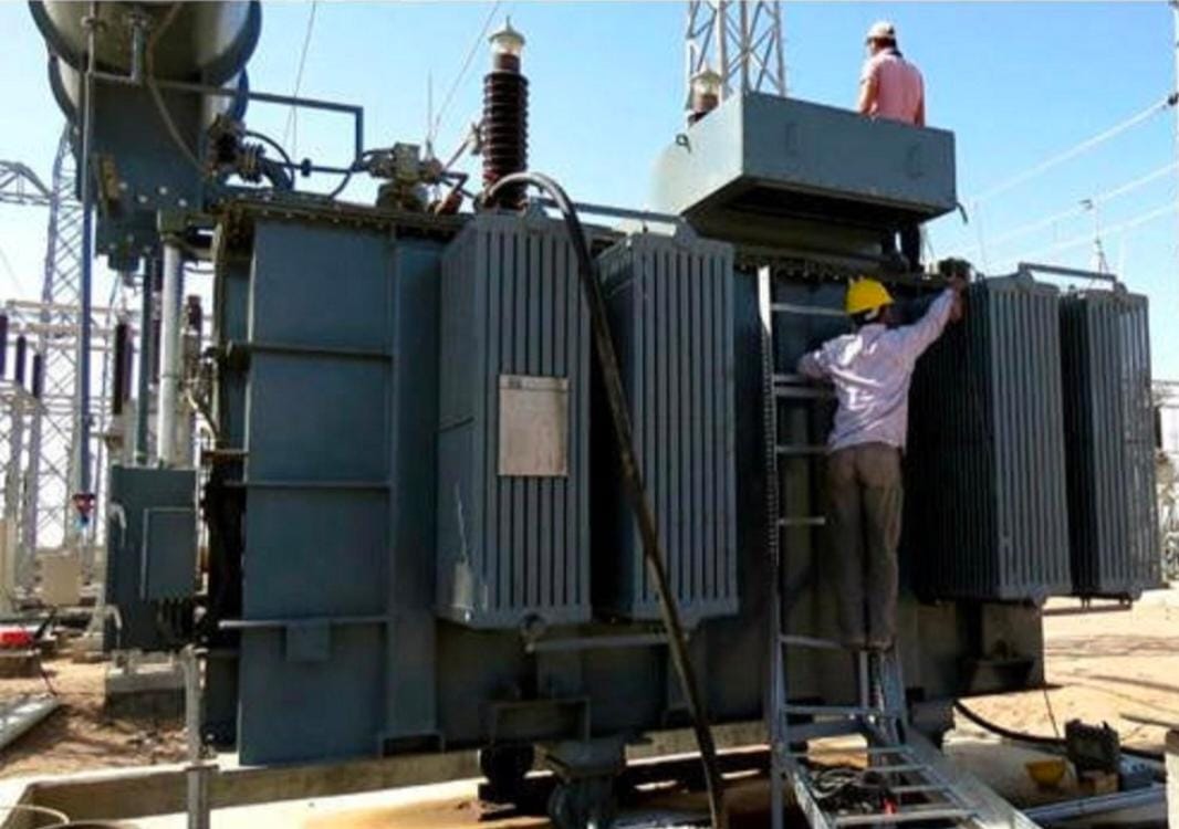 Engineers working on a large oil-filled power transformer